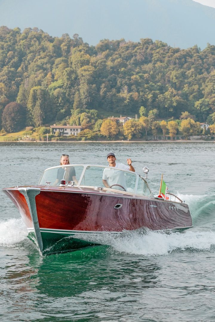 Classic wooden Riva boats glide through blue waters near Italian lakeside villas.