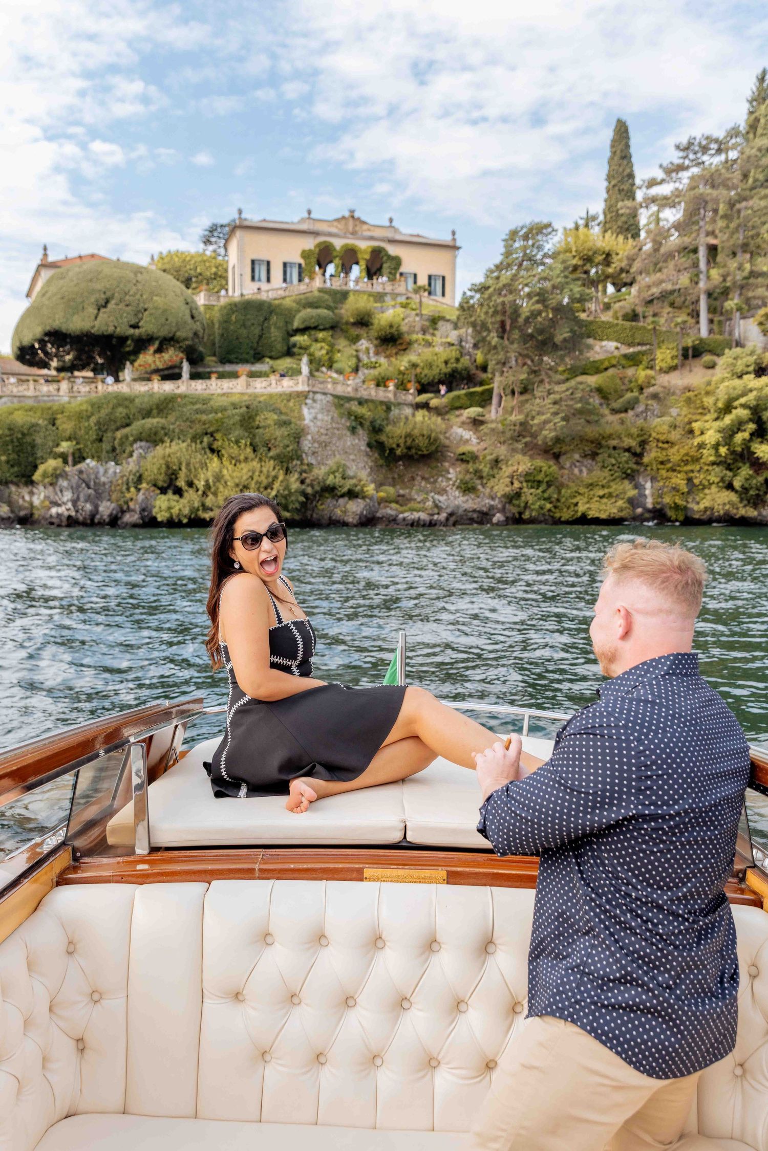 Scenic boat tour along Lake Como's shoreline with elegant villa and cypress trees.