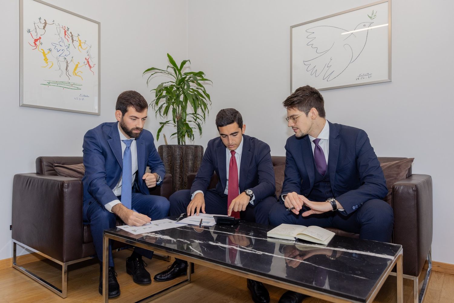 Contemporary office space with professionals working and artwork displayed on walls.