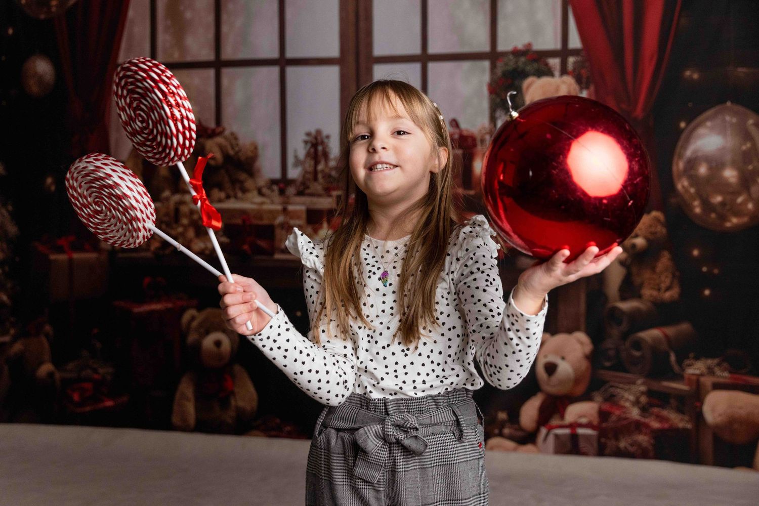 Child in spotted dress twirling with Christmas decorations against dark backdrop with red lights.