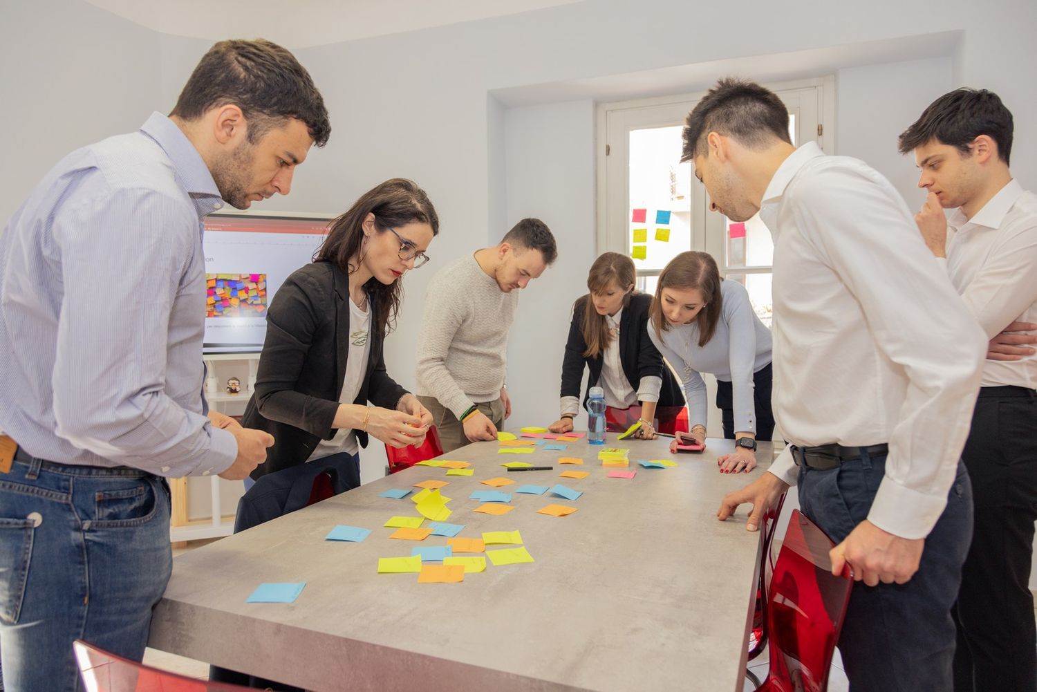People participating in an interactive business workshop with colorful sticky notes.
