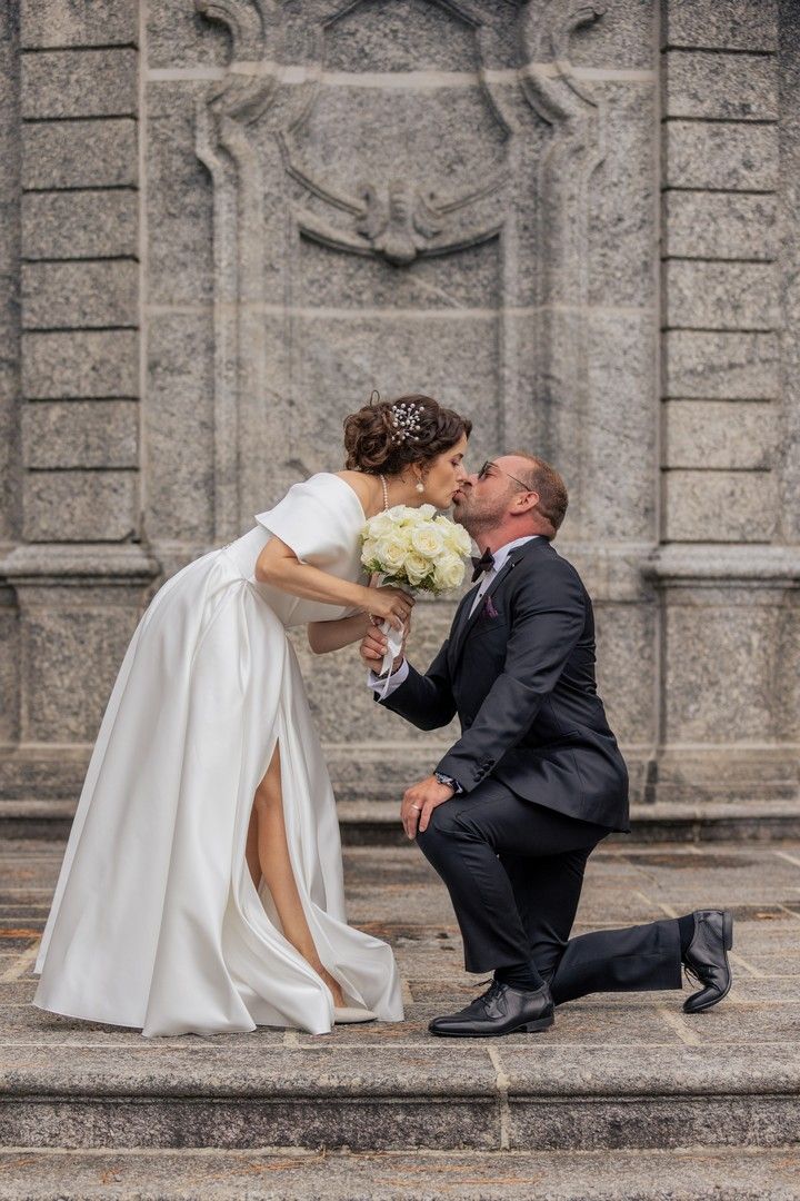 A romantic wedding moment captured on stone steps with ornate architectural details in the background.