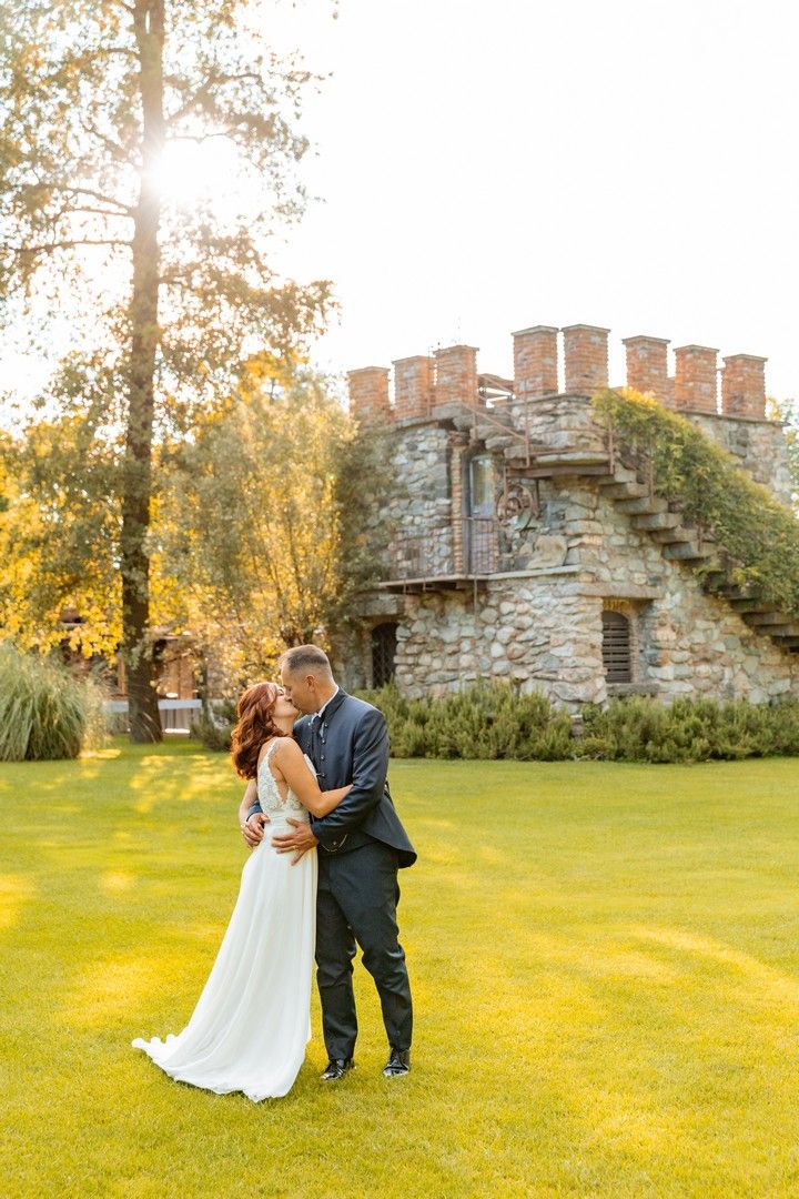 Elegant wedding portraits against stone castle backdrop during golden hour.