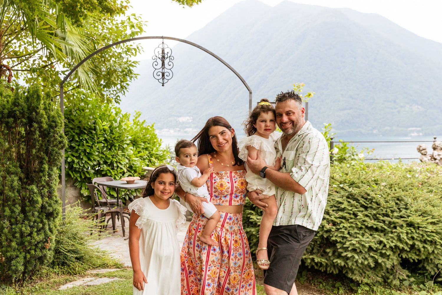 Group portrait in a lush garden setting with mountain and lake backdrop.