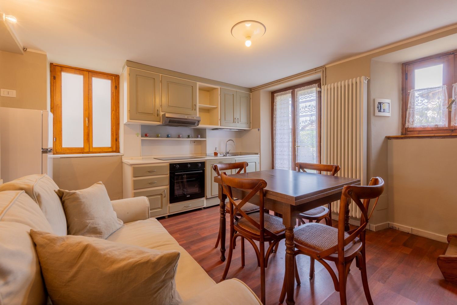 Spacious living room with wooden furniture and natural lighting through large windows.