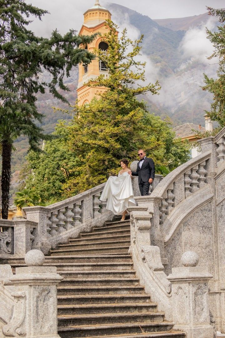 Romantic wedding photos on grand stone steps with mountain and lake backdrop.