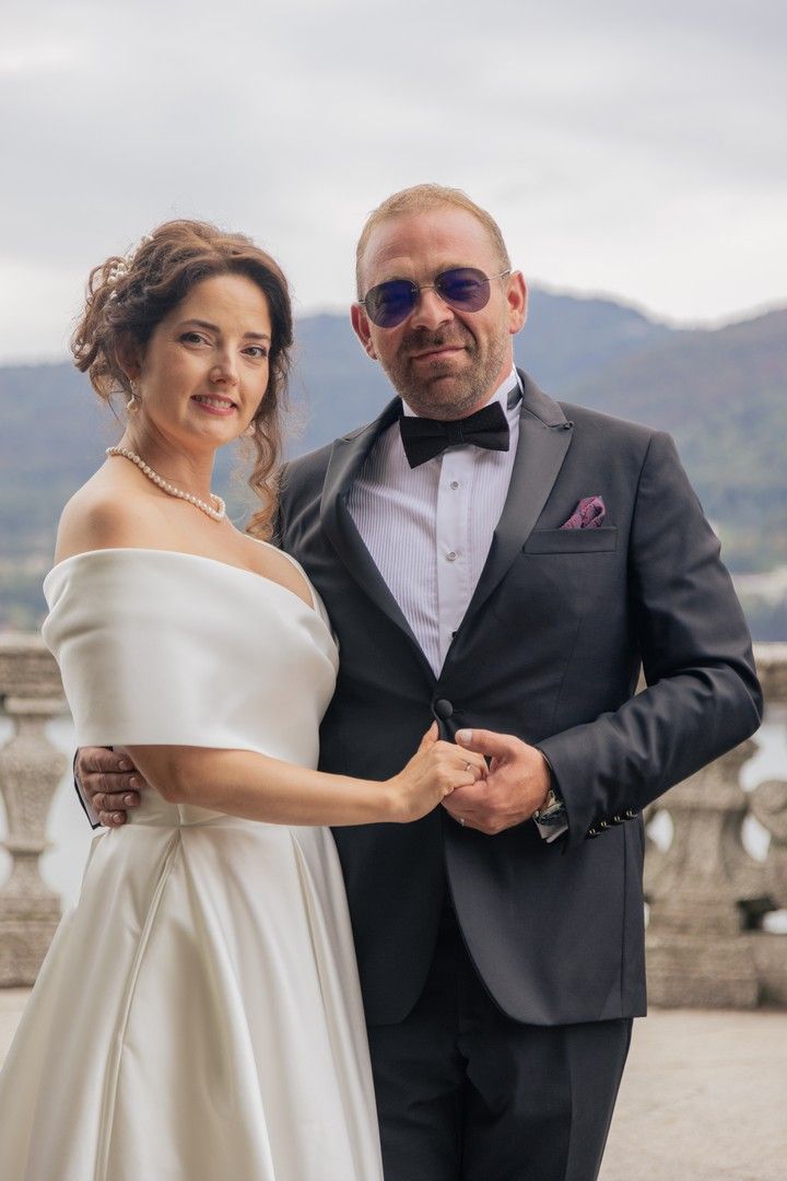 Elegant wedding couple posing on a stone terrace with mountain views.