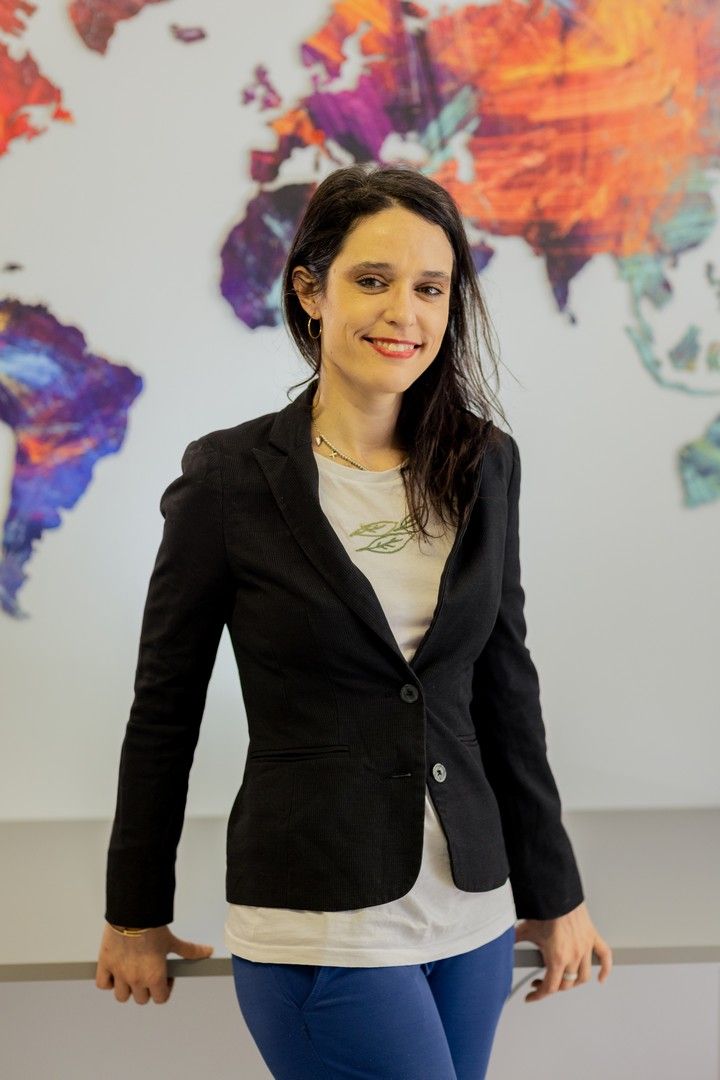 Professional in business attire posing against a colorful abstract wall art background.
