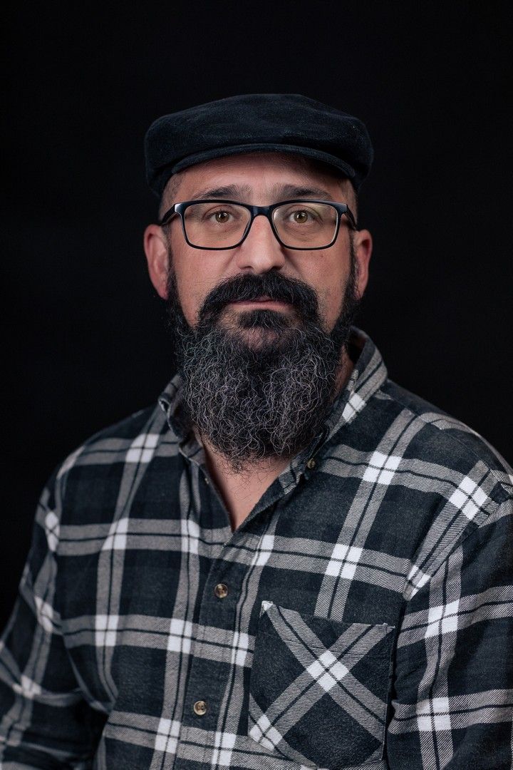 Portrait series of person in plaid flannel shirt and cap against dark background.