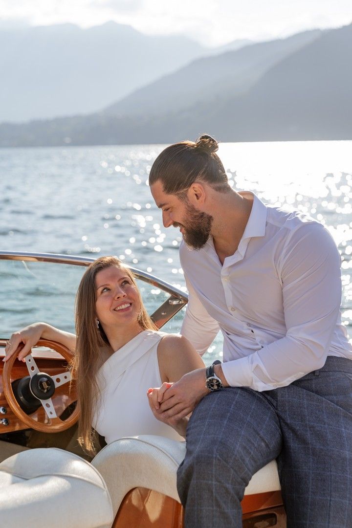 Tender moment captured aboard a vintage wooden boat against a mountainous backdrop.