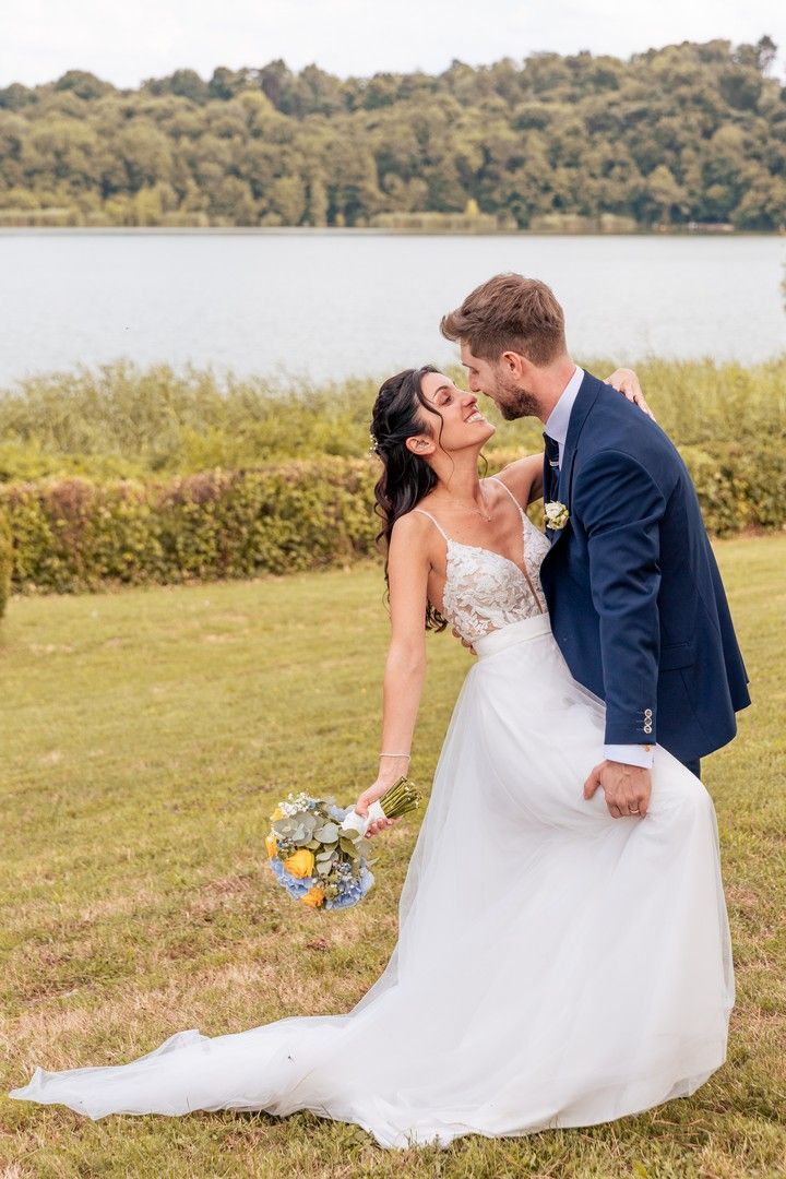 Romantic wedding portraits in a grassy meadow overlooking a serene lake.