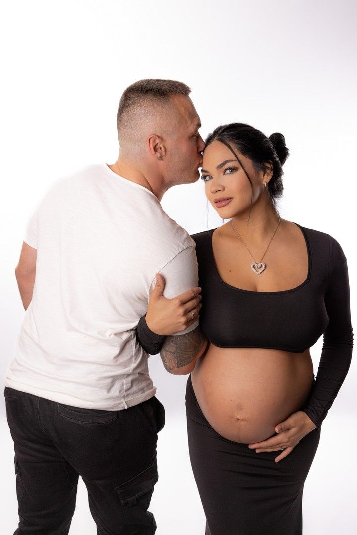 Dramatic black and white maternity photo of couple sharing tender moment.