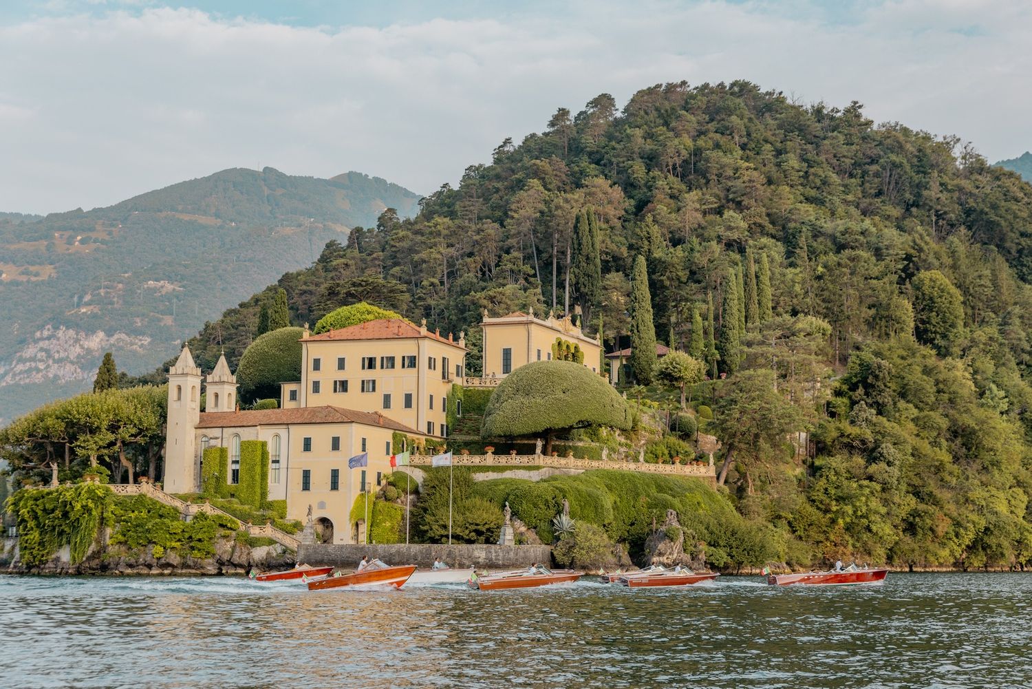 Panoramic view of a luxurious villa nestled on a hillside overlooking an Italian lake.