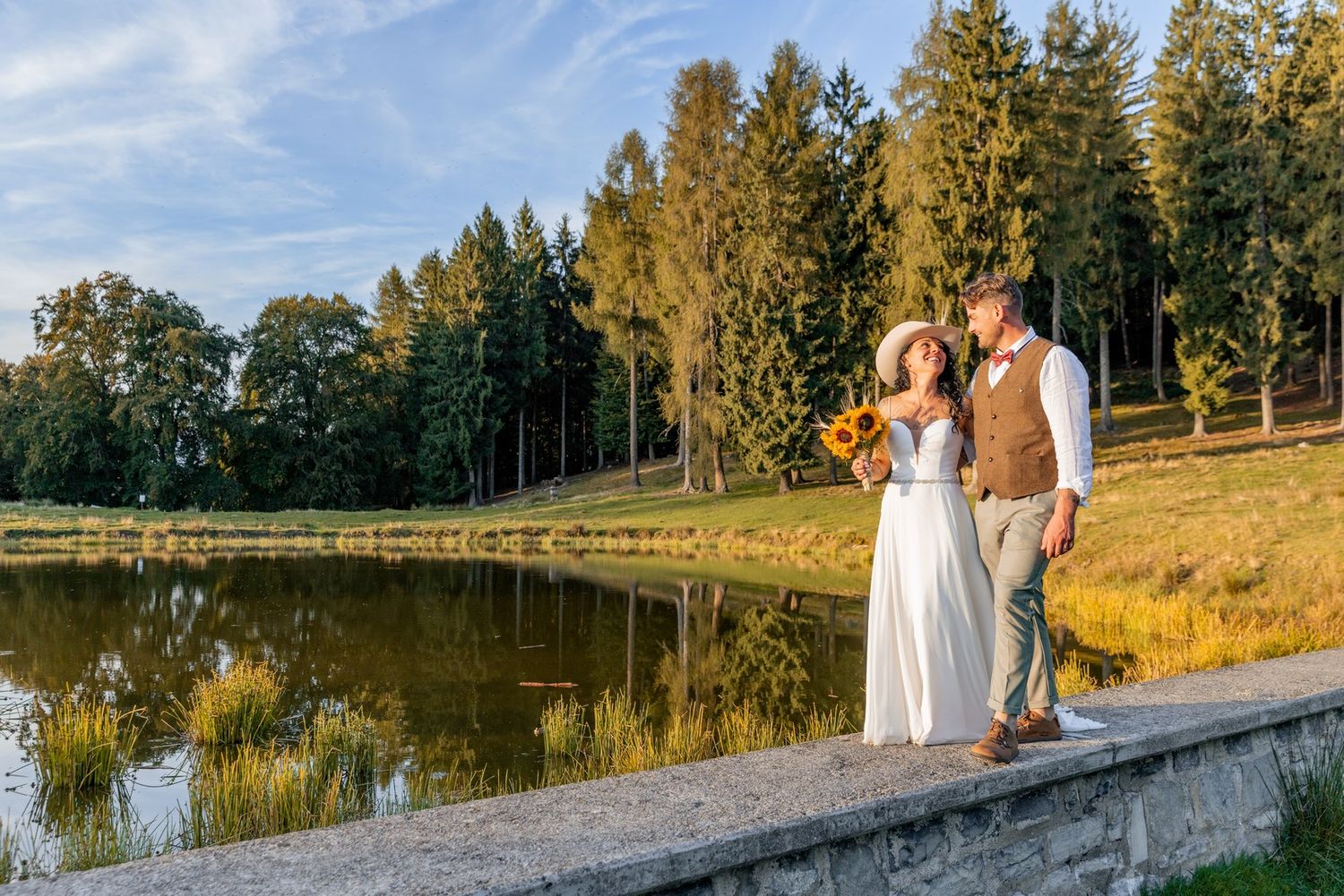 Golden sunset illuminates a lakeside path with evergreen trees creating a romantic backdrop.
