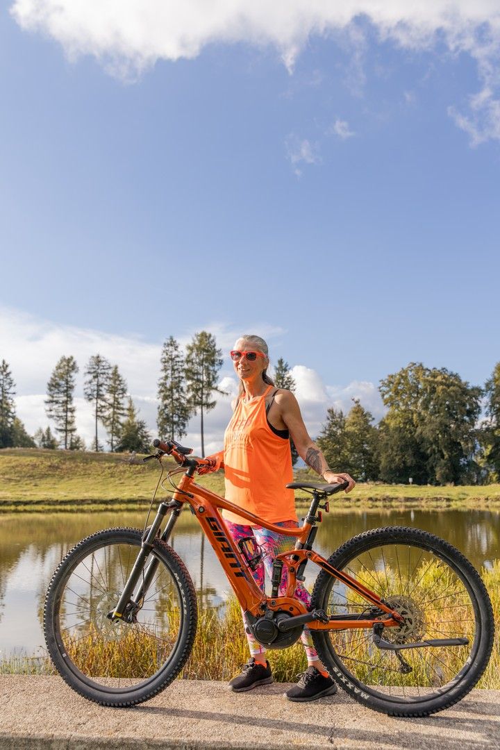 Orange mountain bike photographed in various angles near a lake with mountains in background.