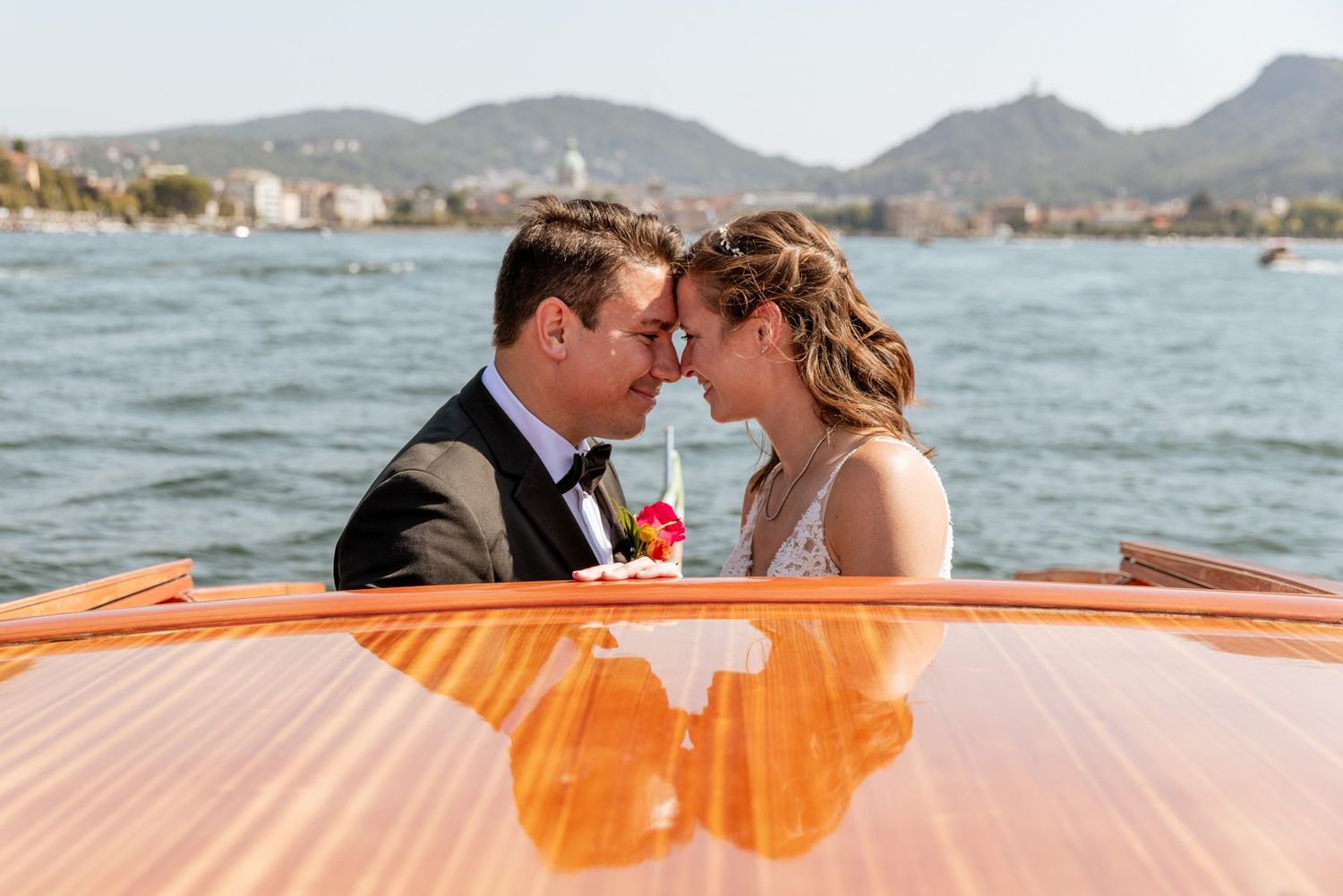 A couple shares a romantic moment on an orange boat in the Mediterranean waters near coastal mountains.