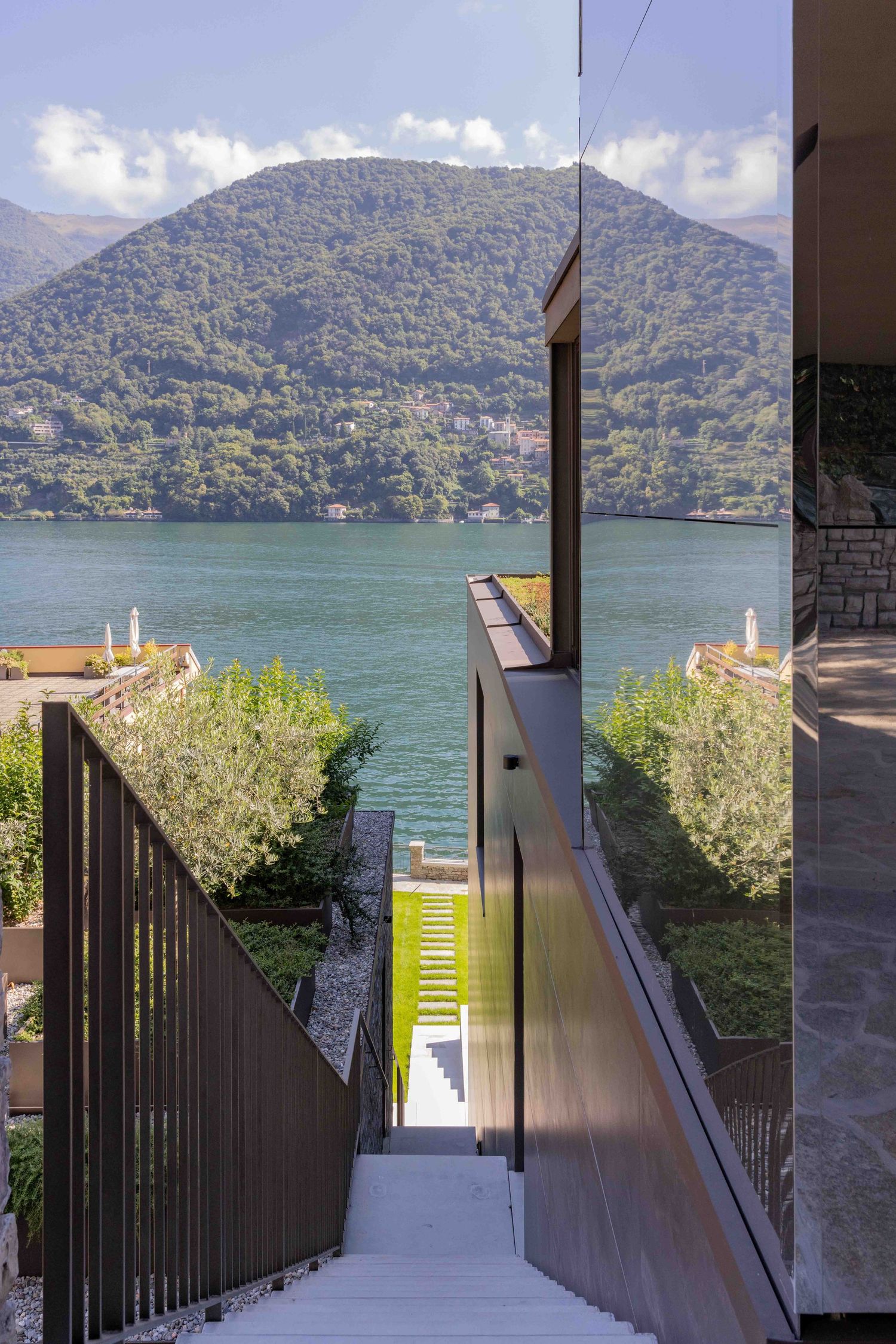 Scenic walkway leading down to lakefront with mountain views and landscaped surroundings.