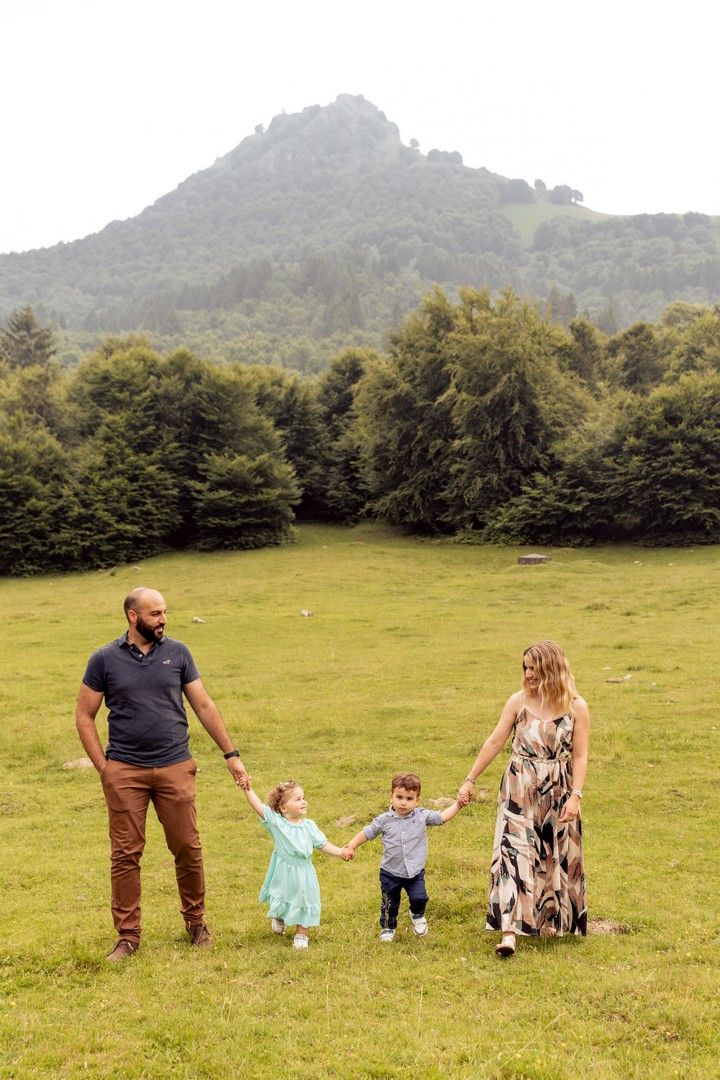 Family walking together across green mountain meadow on overcast day.