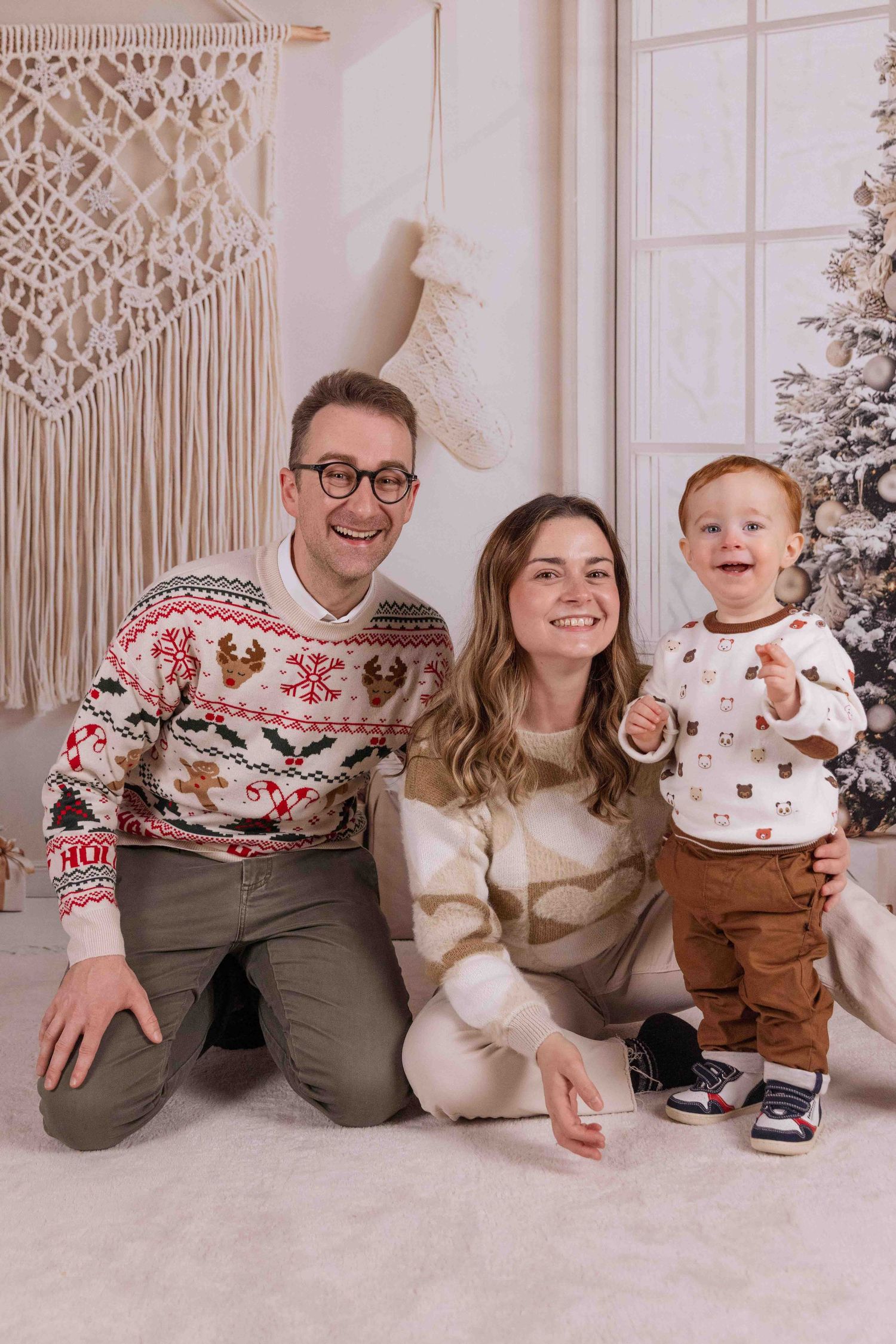 Holiday portrait setup with macrame wall art and decorated Christmas tree in soft lighting.