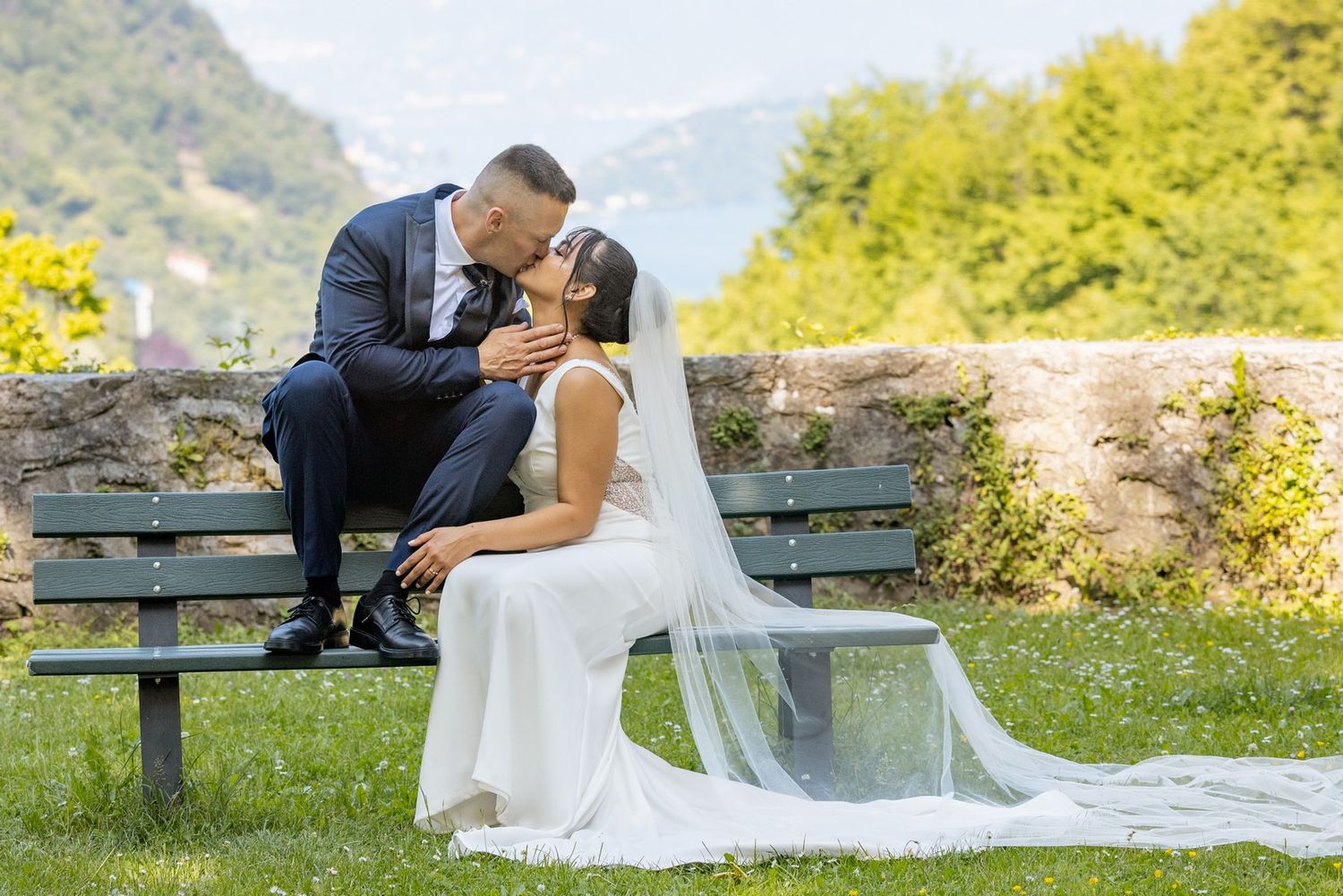 Romantic wedding photos on a park bench surrounded by mountain scenery.