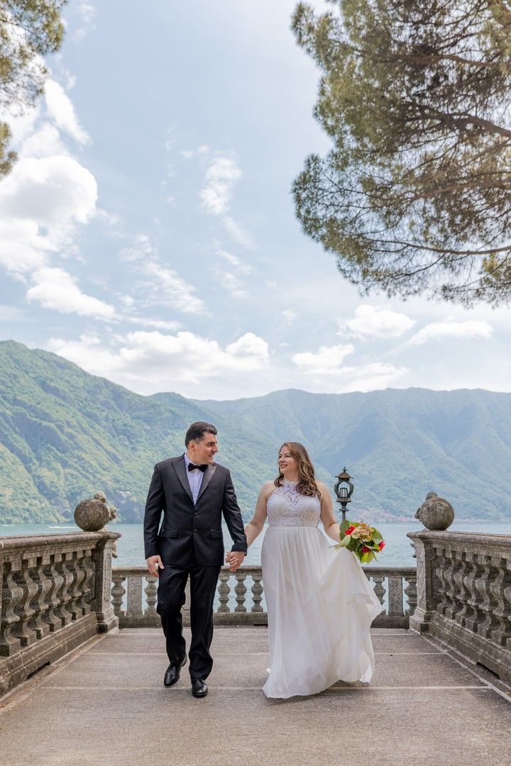 Bride and groom share romantic moments on a stone balcony overlooking scenic mountain views in Lake Como, Italy.