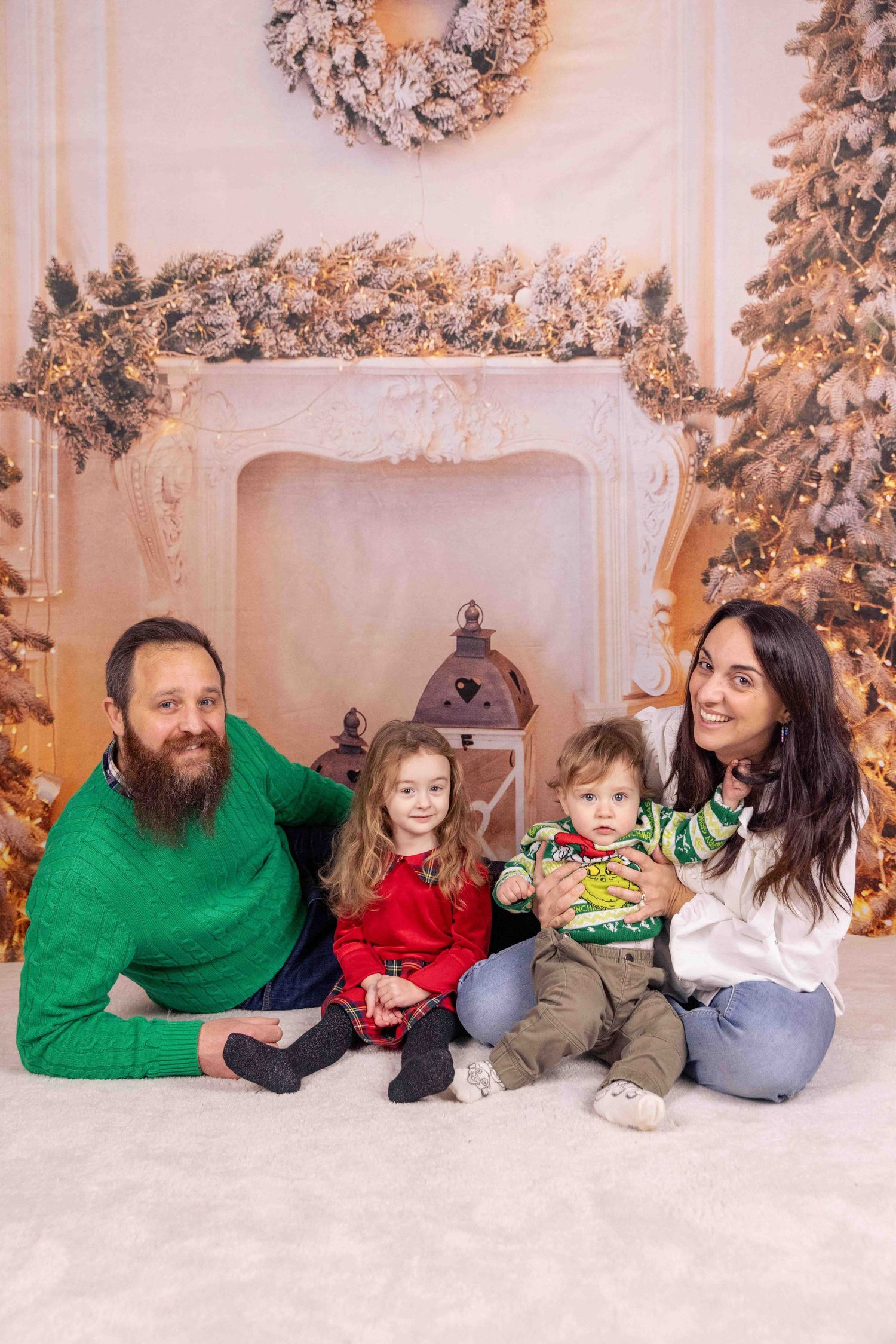 Family lying on white floor with Christmas decorations and snowy trees in background.