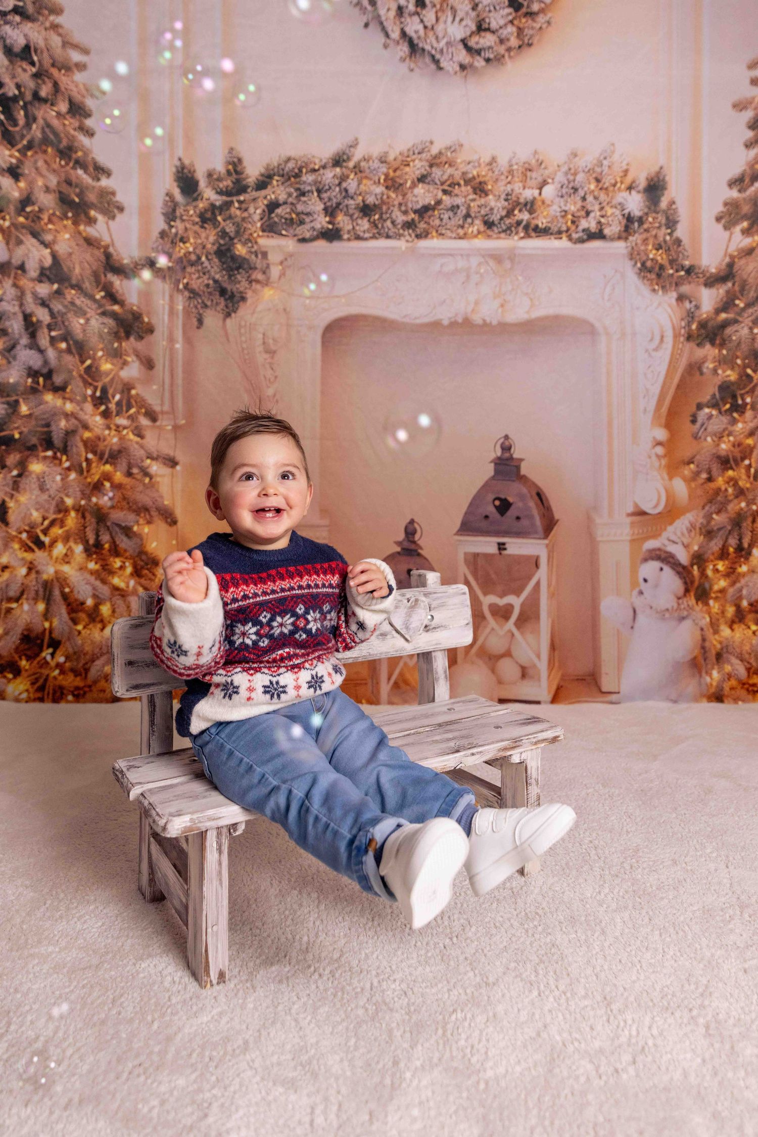 Child in festive sweater plays on rustic wooden bench against snowy winter backdrop.