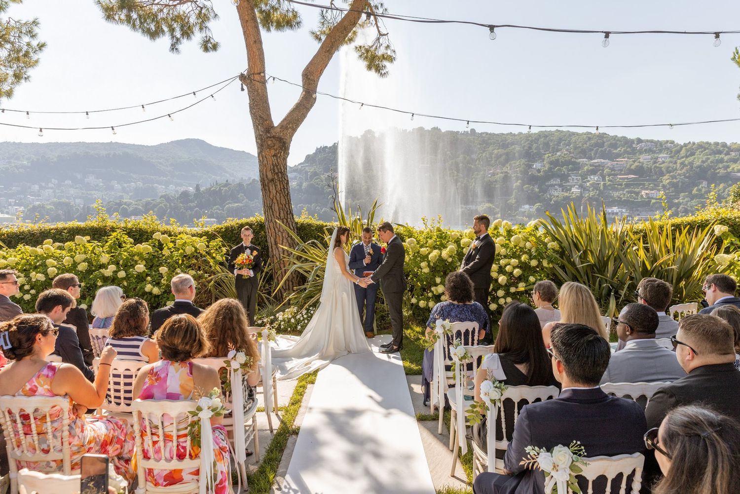 Outdoor wedding reception setup with string lights and mountain views.
