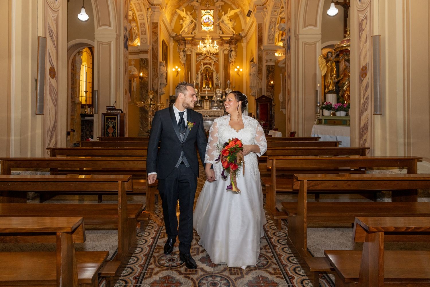 Wedding ceremony in an ornate cathedral with golden baroque details and warm lighting.