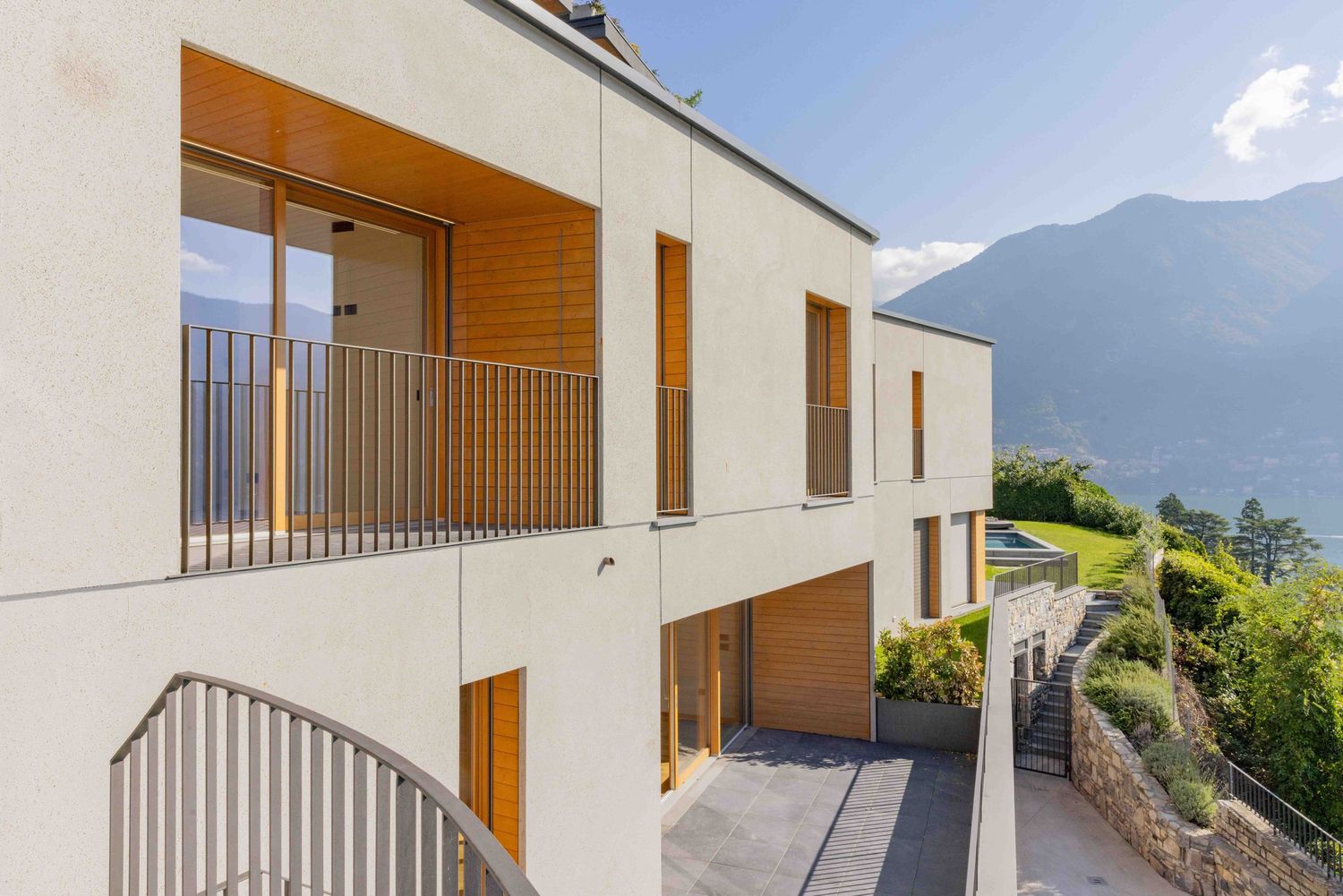 Modern white residential building exterior with wooden accents and mountain backdrop.