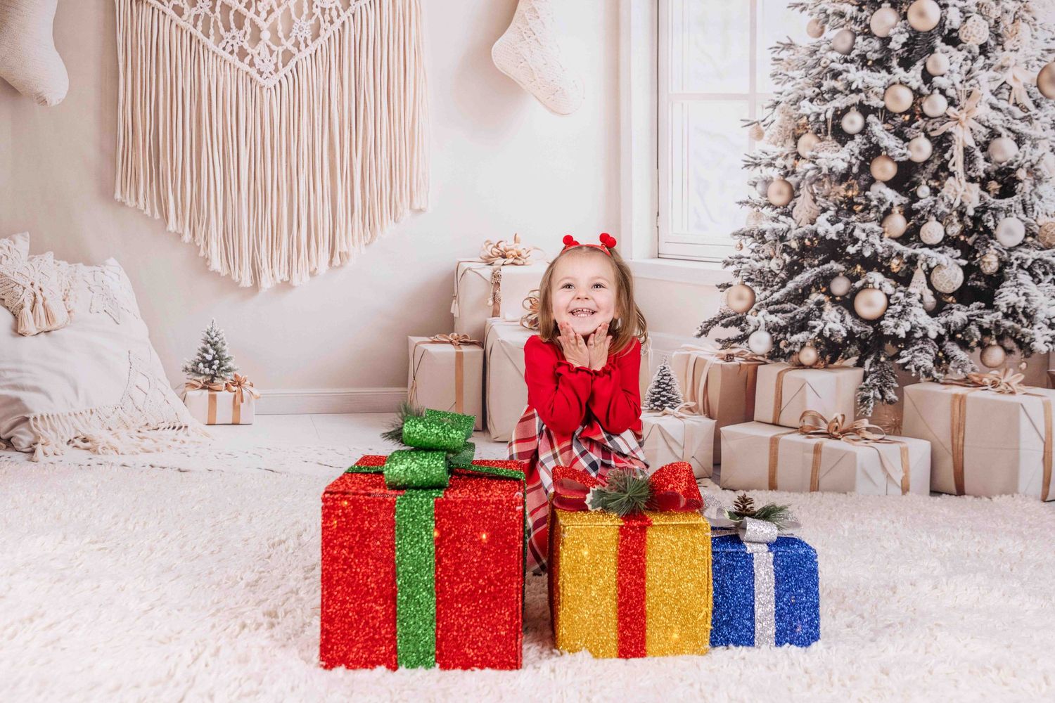 Colorful wrapped Christmas presents arranged in front of white decorated Christmas tree.