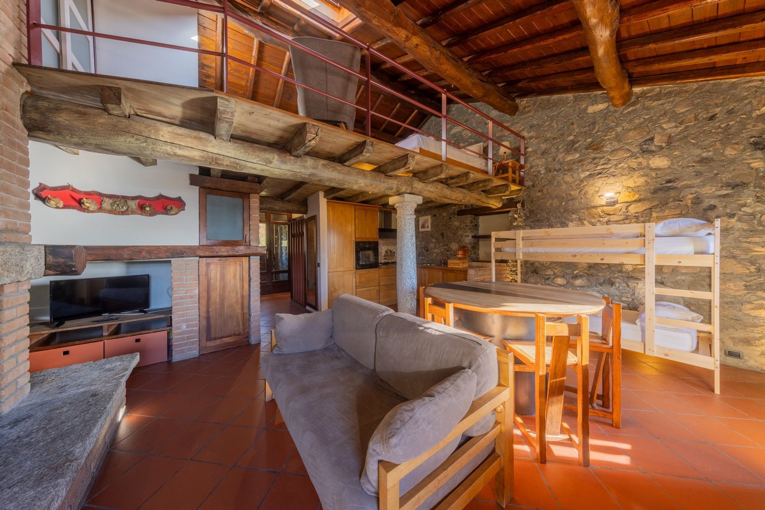 Rustic interior space with exposed wooden beams and stone walls illuminated by warm lighting.
