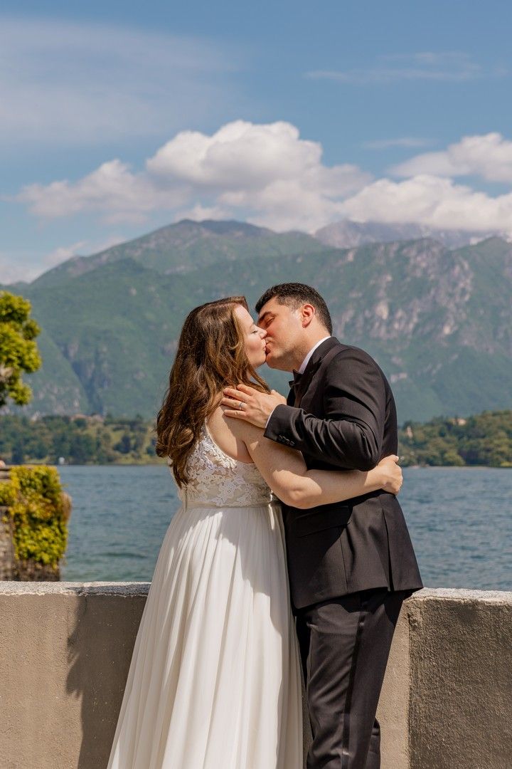 A romantic wedding photoshoot on a lakeside terrace with mountains in the background.