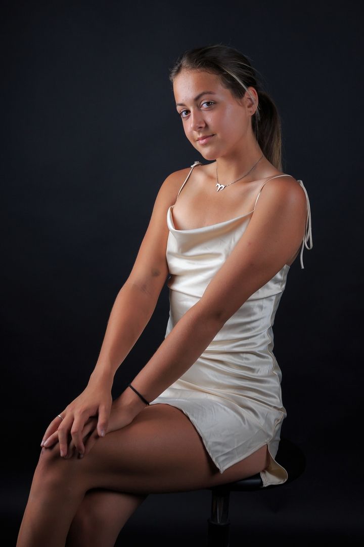 Artistic photo series showing poses in a white satin top against dark background.