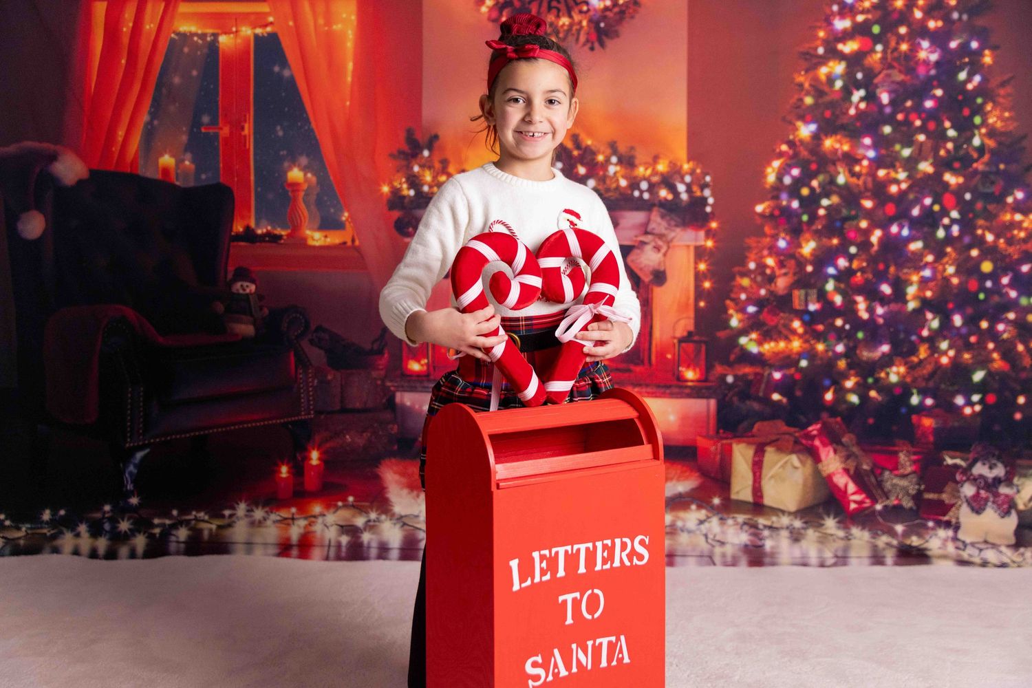 Red mailbox for Santa letters against Christmas tree background.
