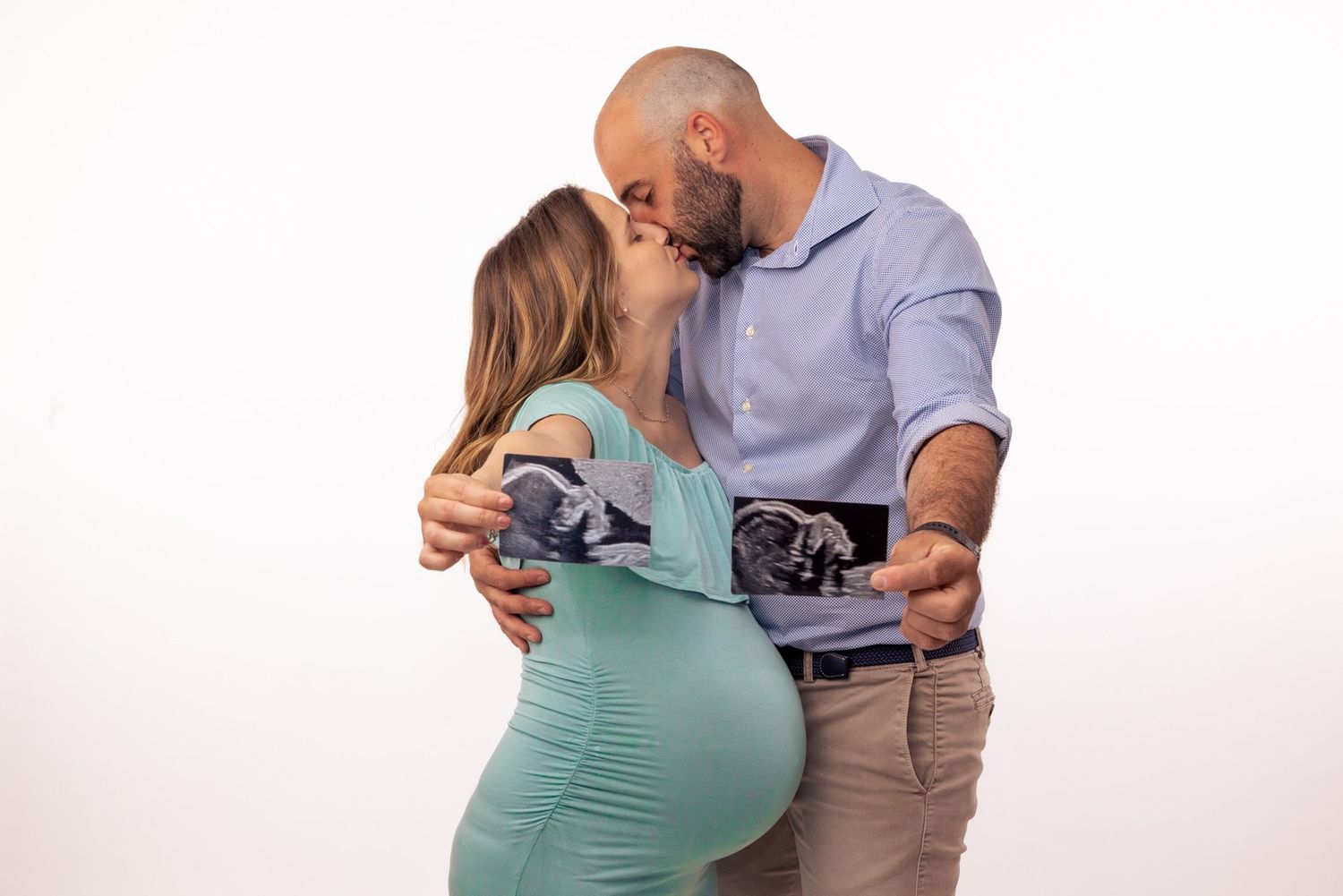 Couple in casual attire sharing tender moment during maternity photo session.