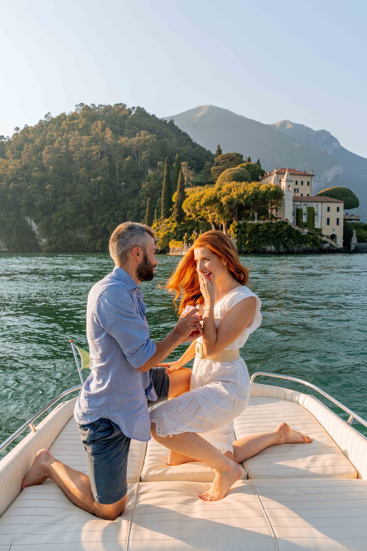 Romantic boat proposal on Lake Como with historic Italian villa in the background.