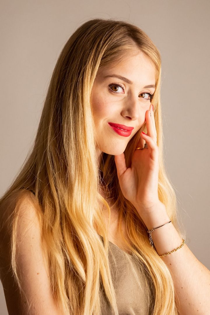 Studio portrait with soft lighting and neutral beige background.