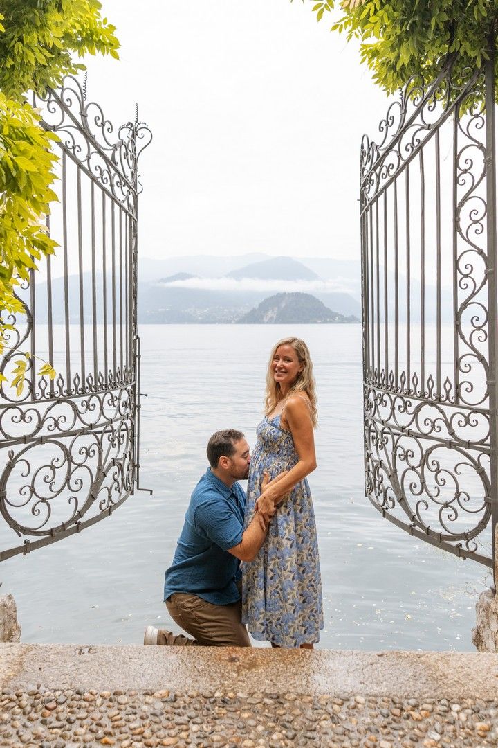 Couple shares romantic moment by ornate gate overlooking mountain lake view.