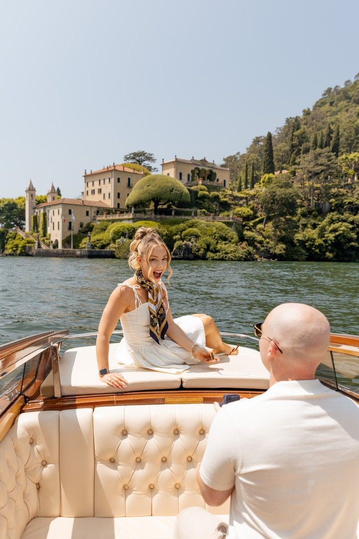 A sunny afternoon boat ride on Lake Como with elegant villas and cypress trees dotting the shore.