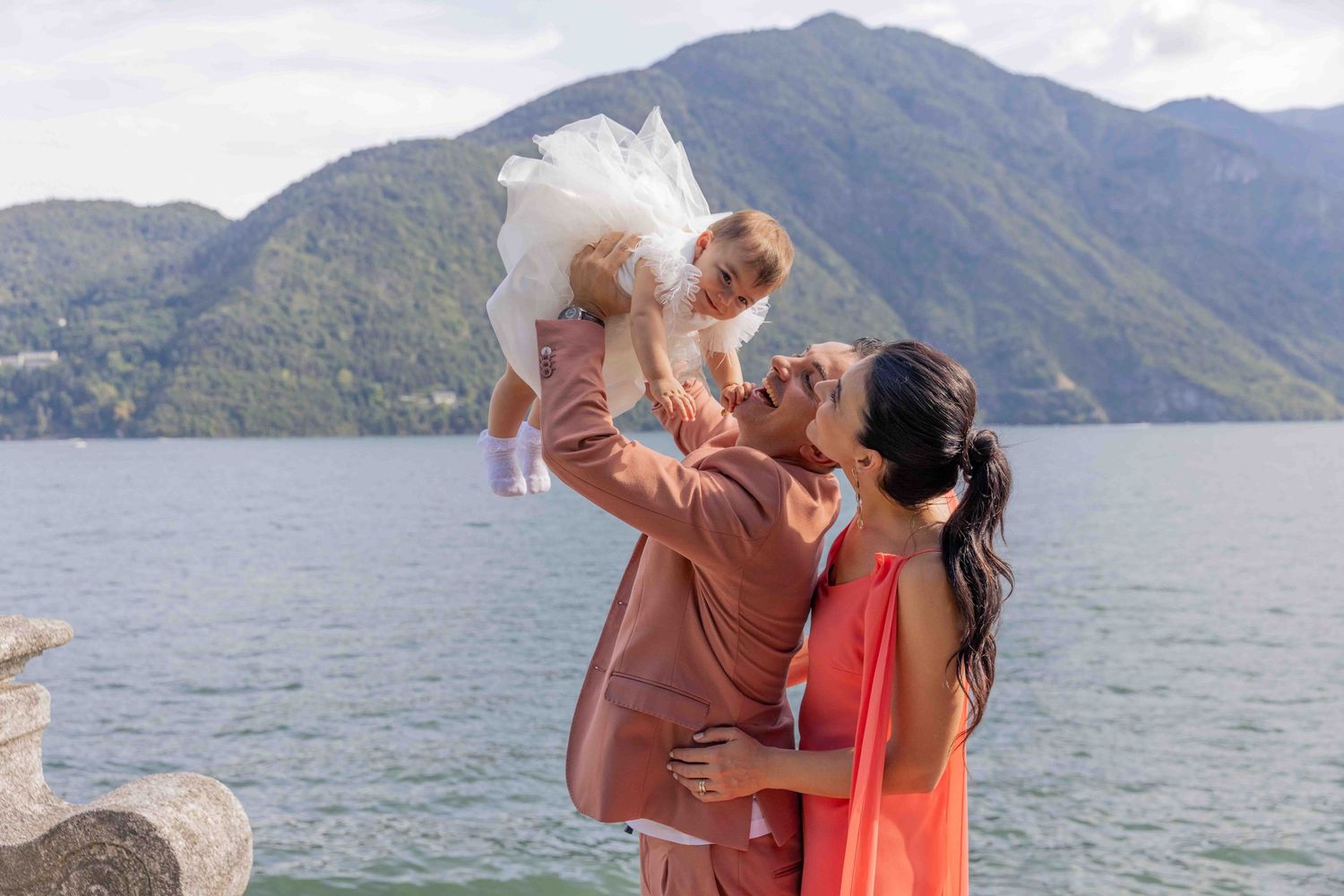 Group photo session by a scenic lake with mountains in the distance.
