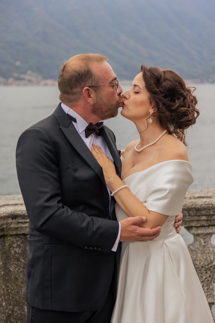A romantic wedding moment captured on a terrace overlooking an Italian lake and mountains.