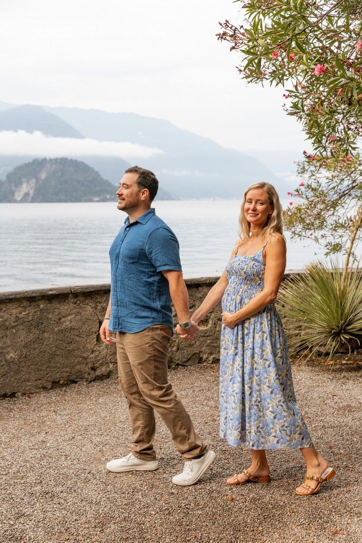 Playful couple poses on gravel path with scenic lake and mountain views.