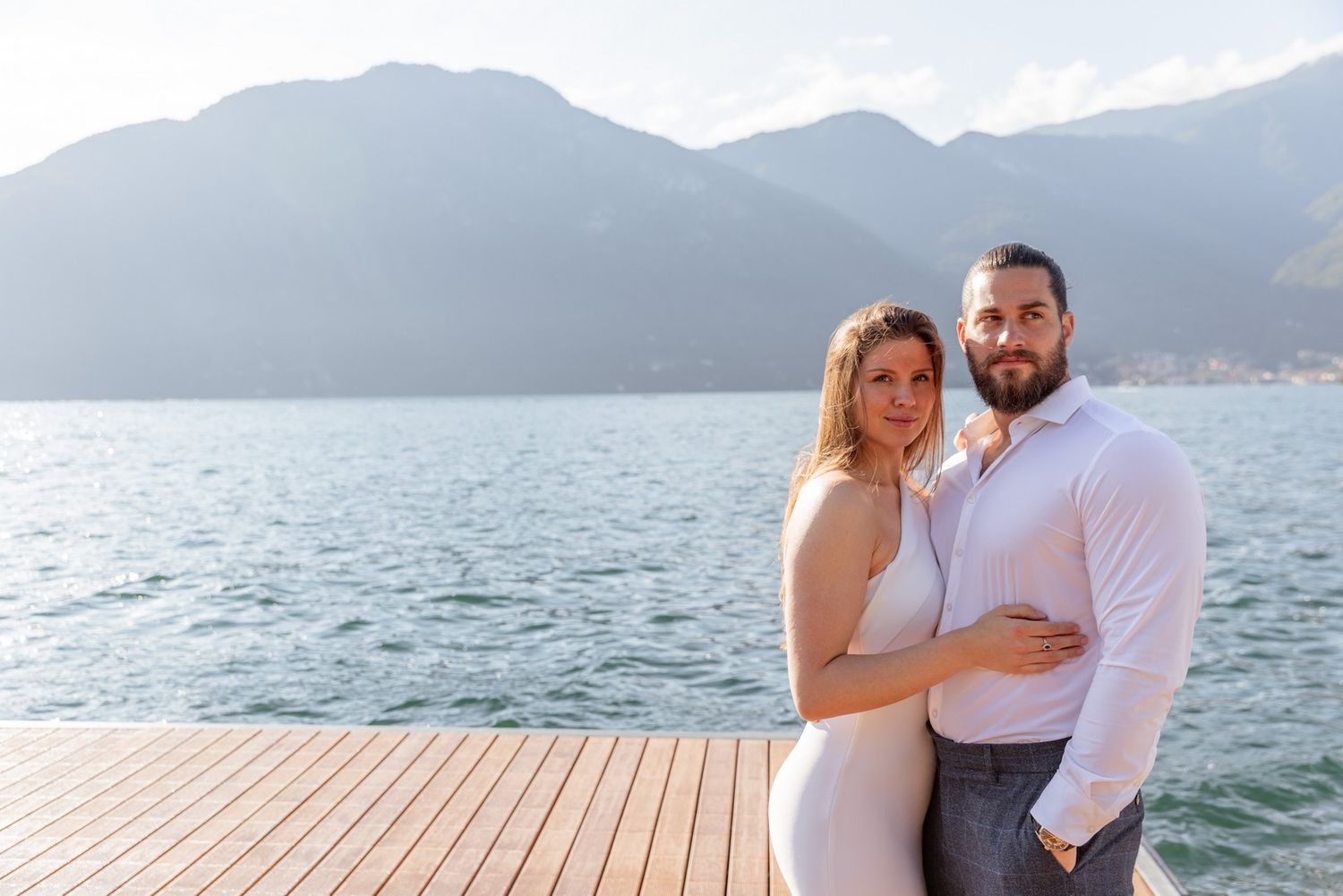 Couple sharing romantic moments on a boat dock with mountain views.