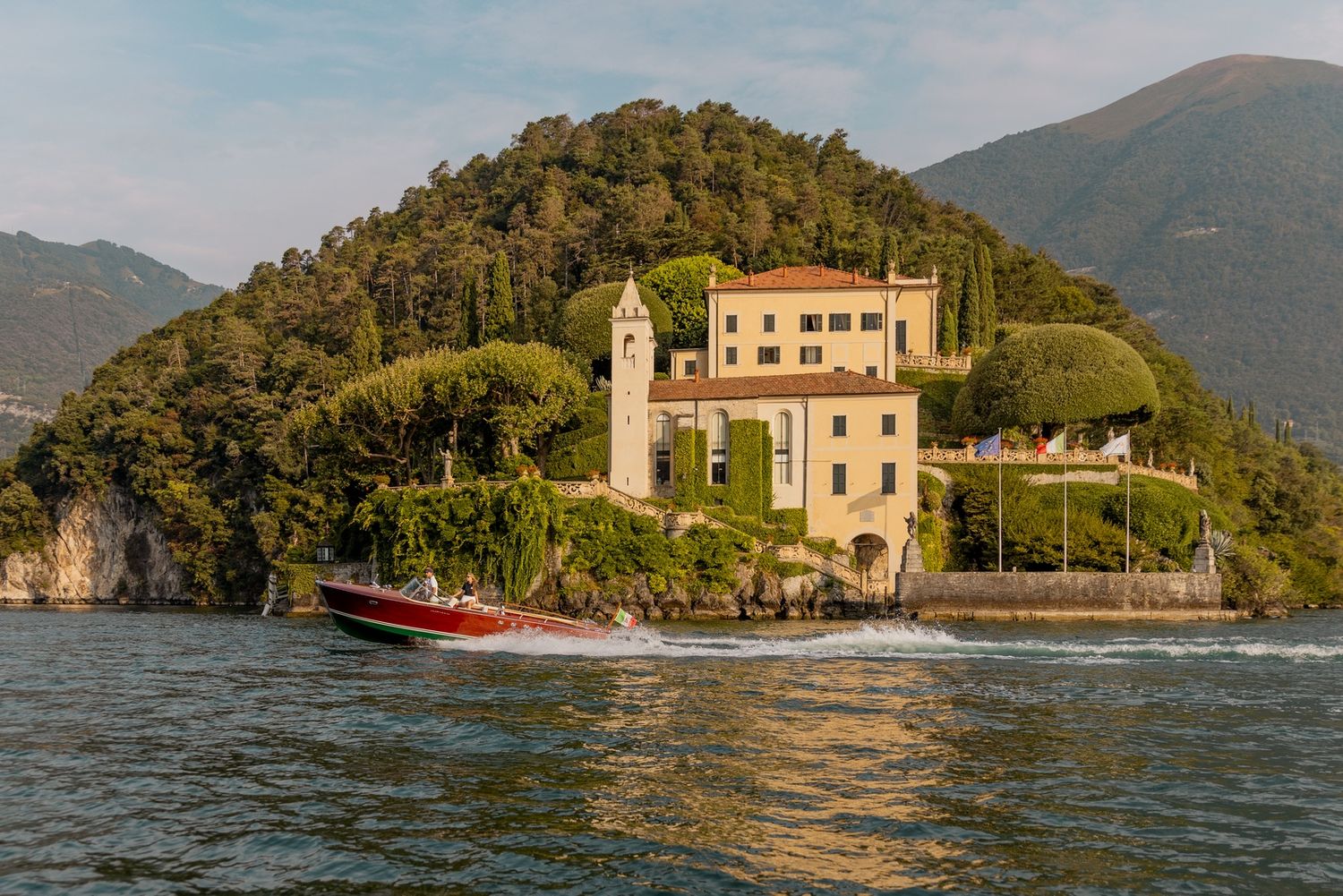 Mahogany boats cruise along the shoreline of Lake Como with historic villas visible.