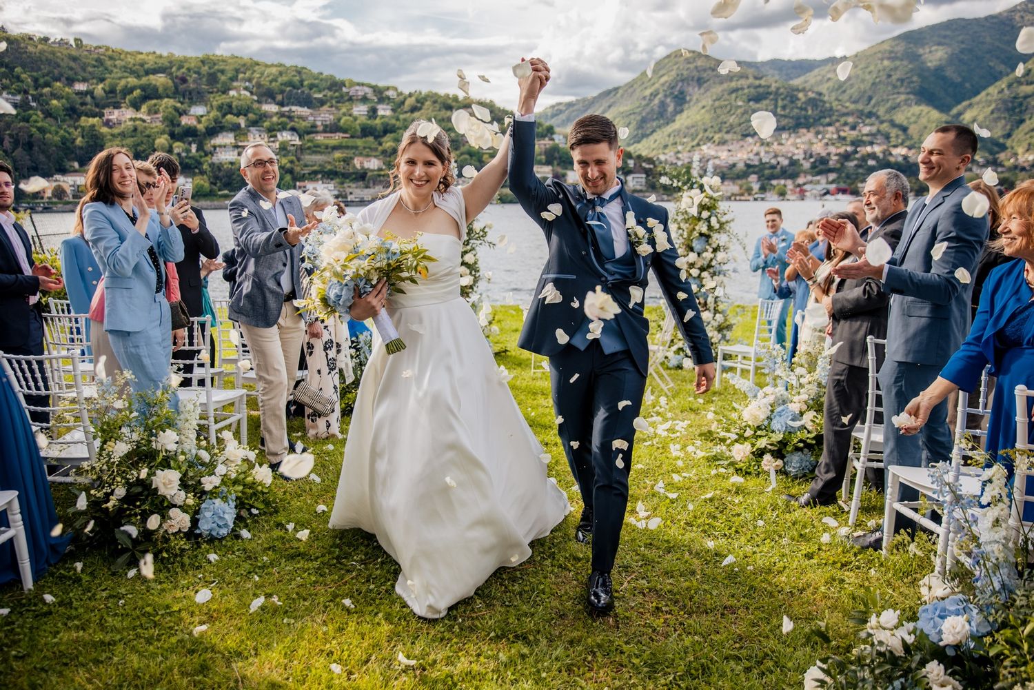 Wedding guests throwing flower petals during an outdoor mountain celebration.