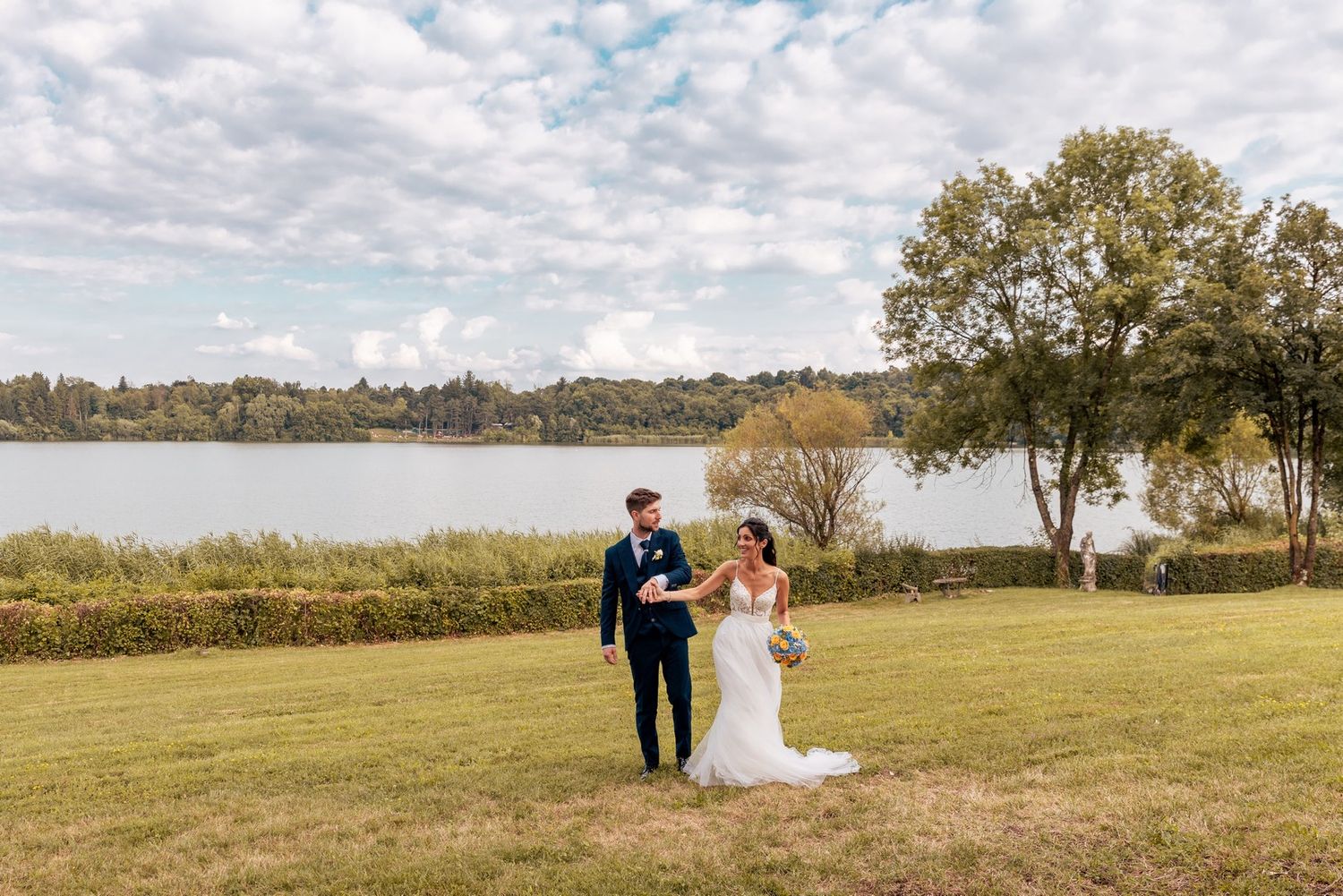 Wedding photography in a serene meadow with trees and natural landscape.
