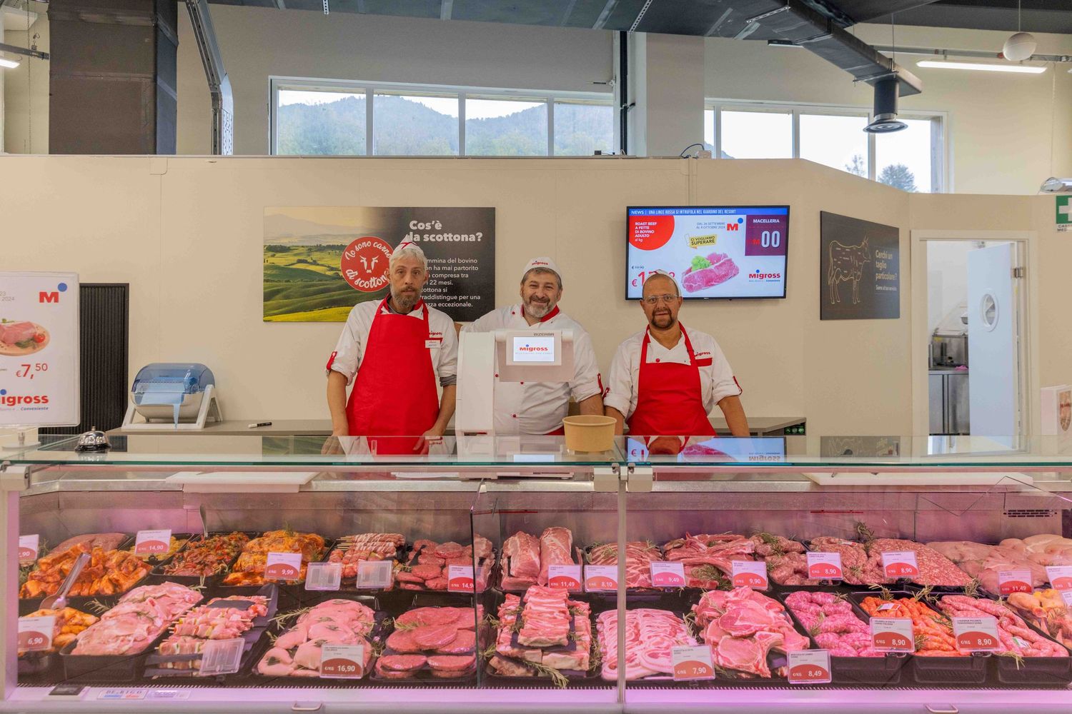 Long meat counter display case with fresh cuts of meat in retail store.