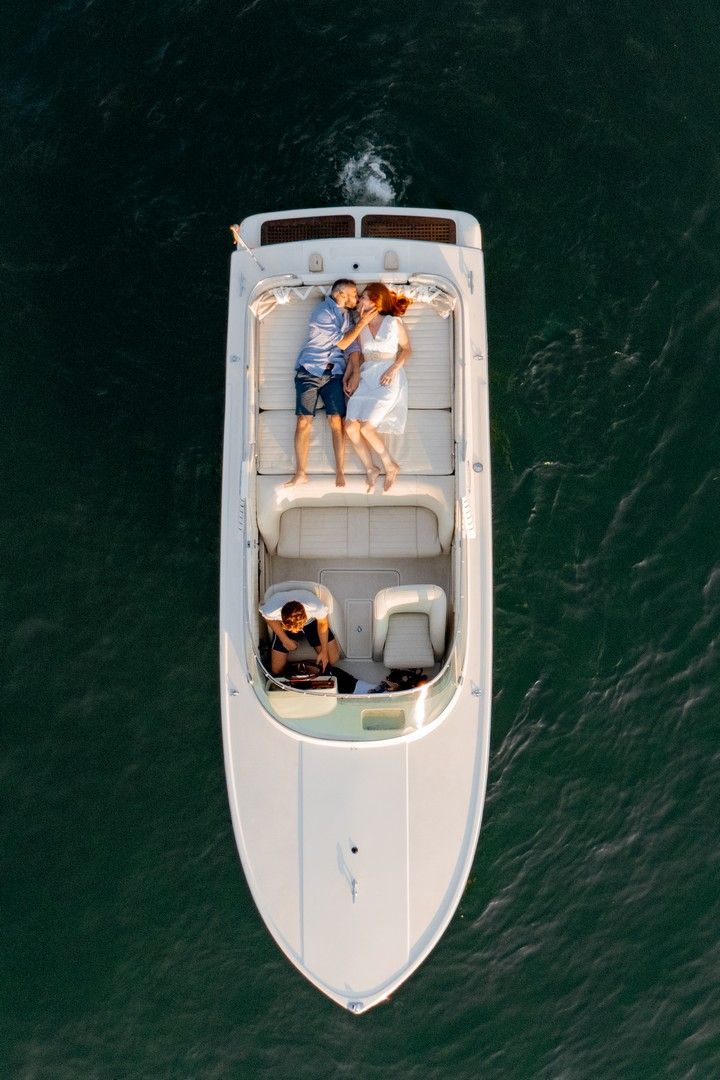 Aerial view of white speedboat on dark waters with passengers enjoying a sunny day.