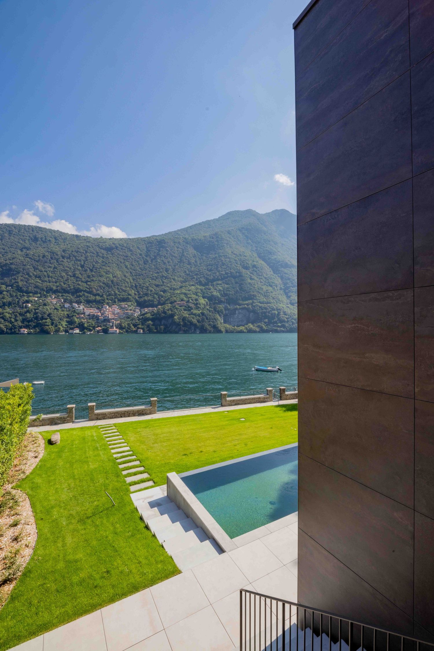 Modern lakefront villa with infinity pool overlooking mountains and pristine waters.